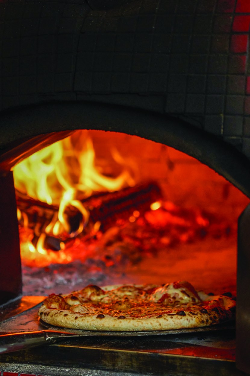 A pizza baking in the flames of the Mr. CIAO wood-fired oven